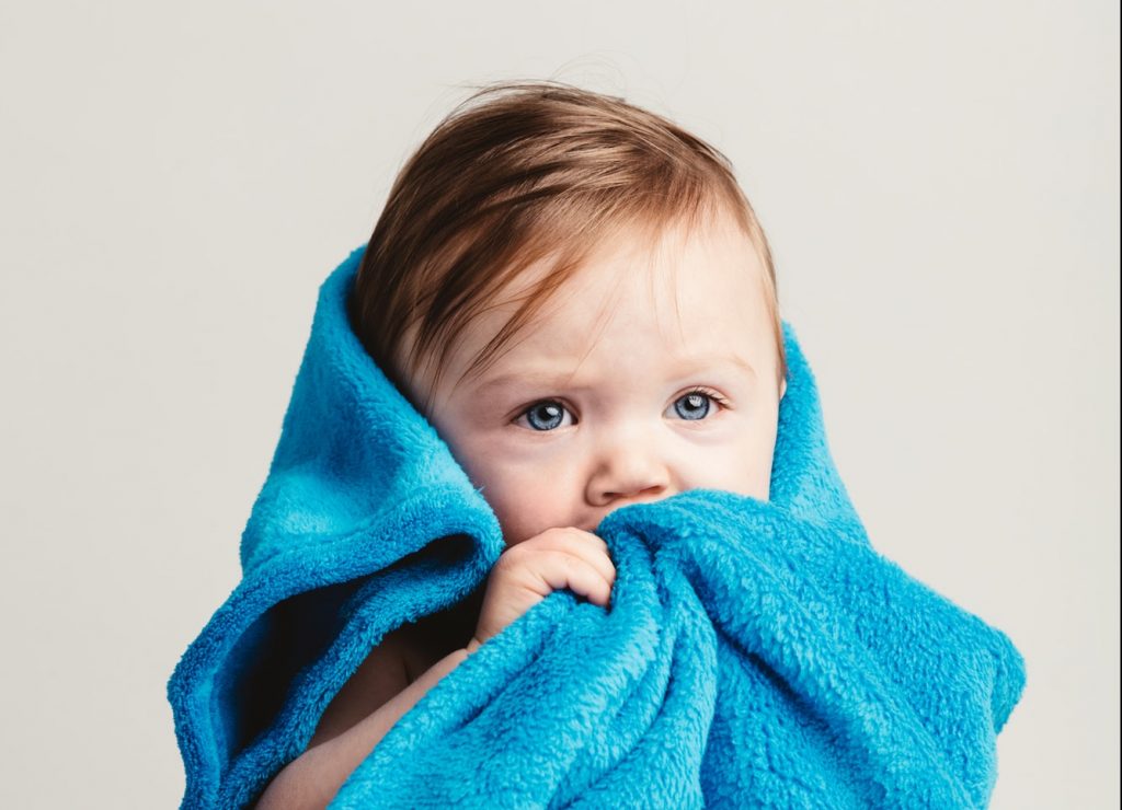 Little baby girl tucked in a cozy blue blanket.